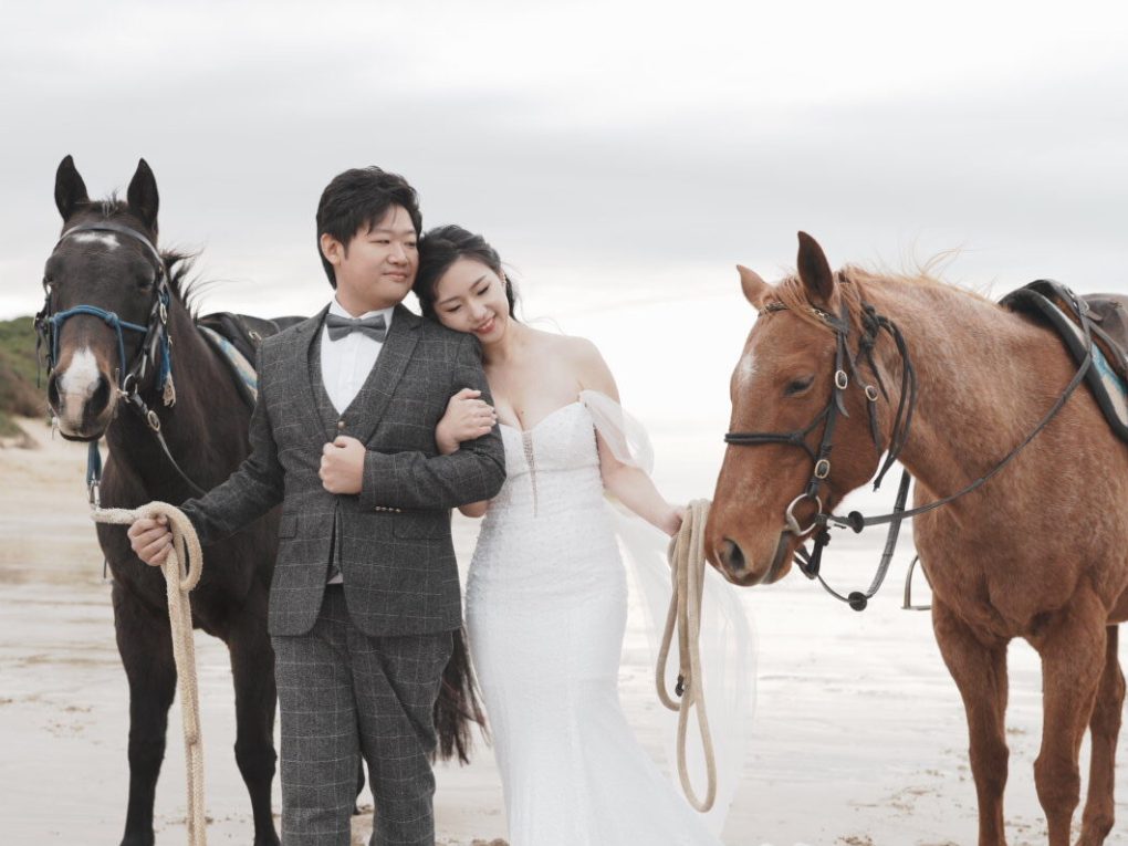 NEO07246 a couple of people that are sitting on a horse on a beach